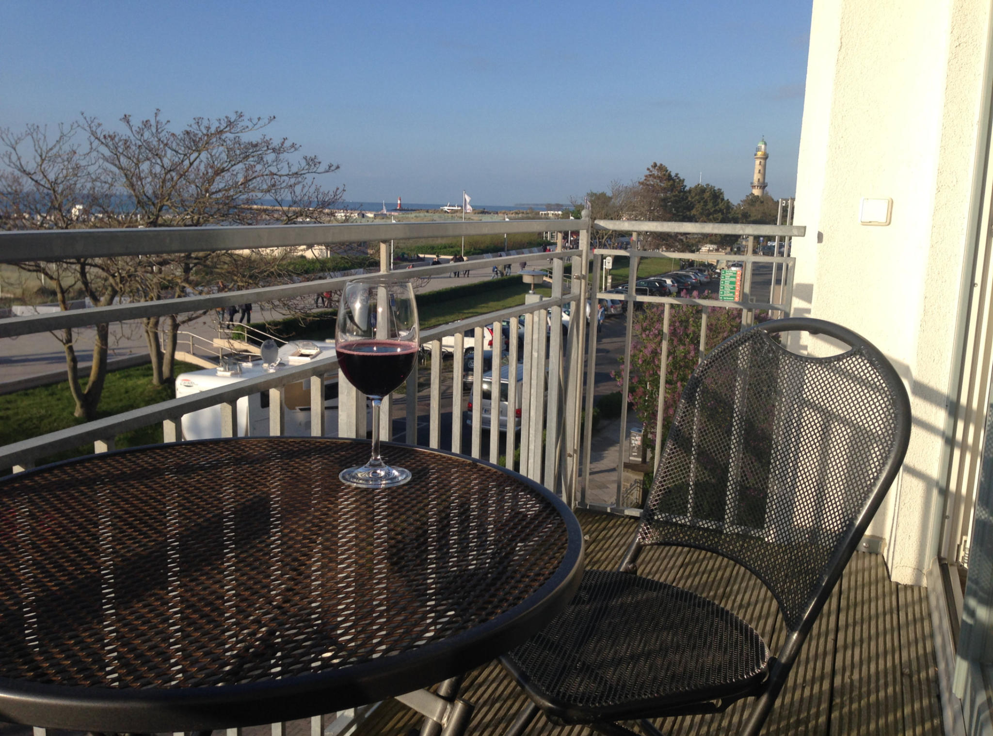 Blick vom Balkon über die Seepromenade zur Ostsee, rechts der Warnemünder Leuchtturm