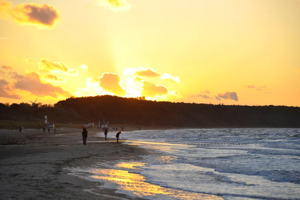 Goldener Sonnenuntergang über der Ostsee, Spaziergänger am Spülsaum des Strandes