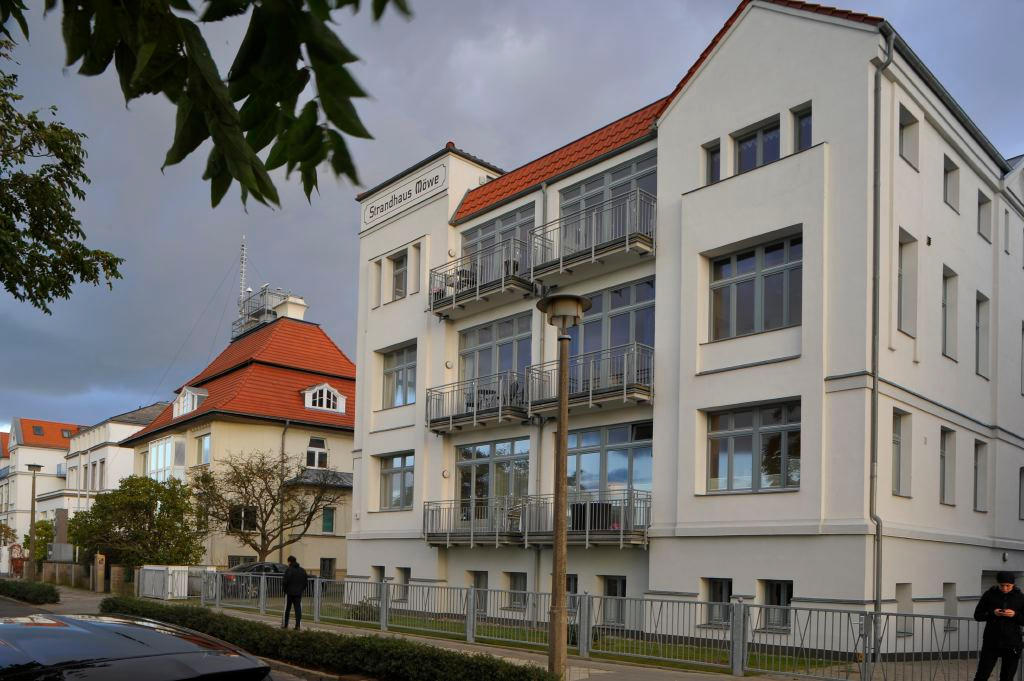 Das Strandhaus Möwe von der Seestraße aus: weißer Altbau mit rotem Dach und Balkonen zur Seeseite